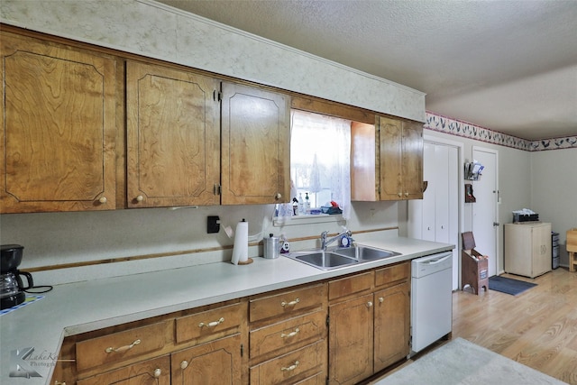 kitchen with sink, light hardwood / wood-style flooring, dishwasher, a textured ceiling, and washer / clothes dryer