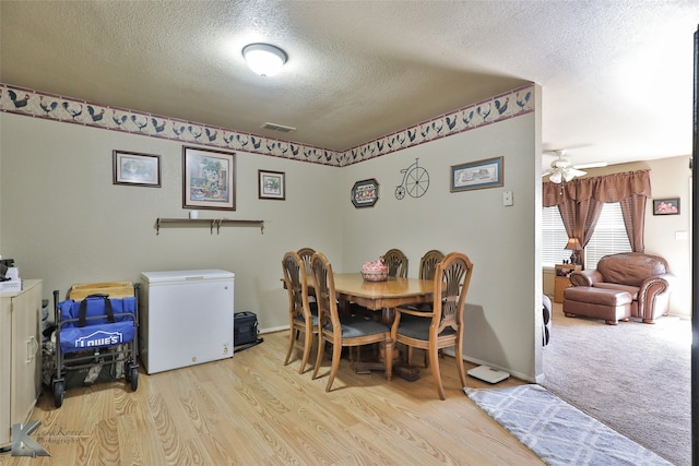 dining area with ceiling fan, a textured ceiling, and light wood-type flooring