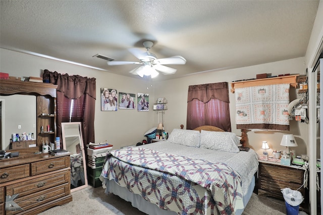 carpeted bedroom featuring ceiling fan and a textured ceiling