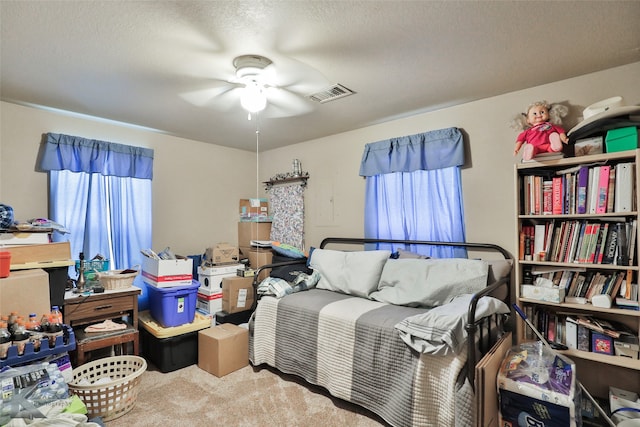 bedroom featuring multiple windows, ceiling fan, a textured ceiling, and carpet