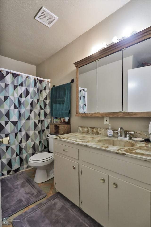 bathroom featuring vanity, a textured ceiling, and toilet