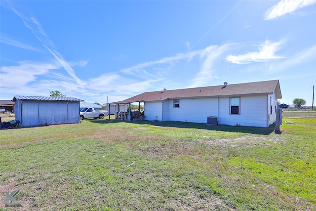 back of house with a shed, central AC, and a lawn