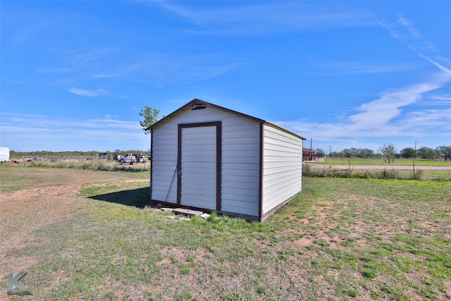 view of outdoor structure with a rural view and a yard