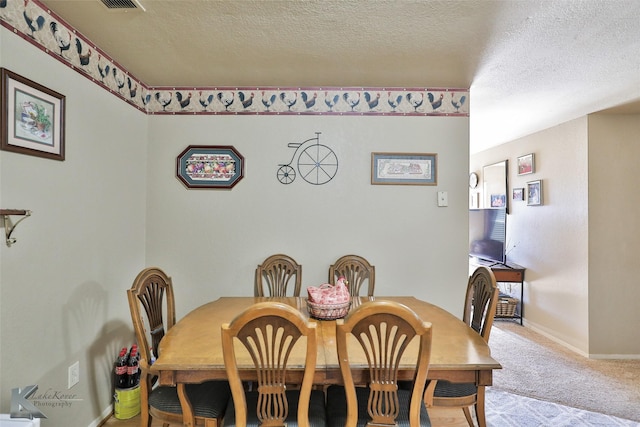 carpeted dining room with a textured ceiling