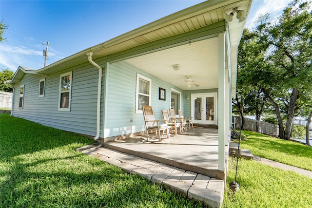 back of property with a lawn, ceiling fan, and french doors