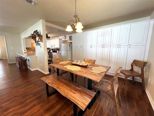 dining space with dark wood-type flooring and a chandelier