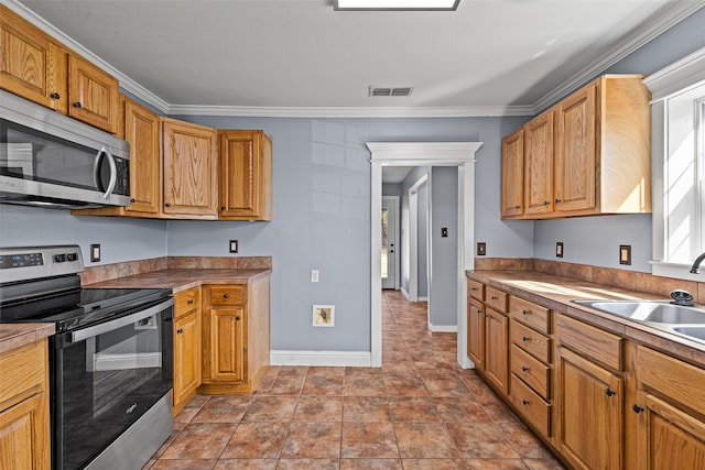 kitchen with sink, ornamental molding, stainless steel appliances, and light tile patterned floors