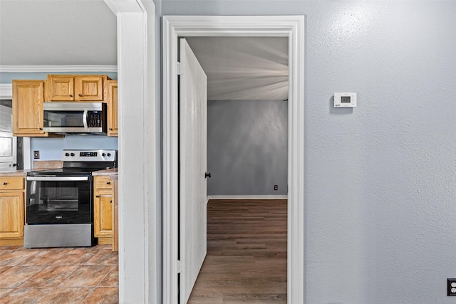 kitchen featuring crown molding, light wood-type flooring, stainless steel appliances, and light brown cabinets