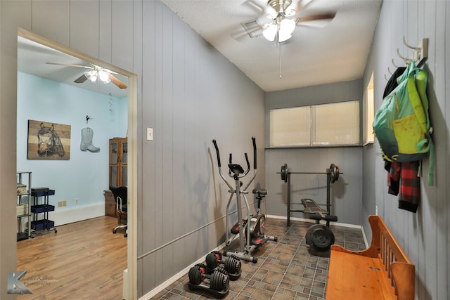 workout area with hardwood / wood-style floors, a textured ceiling, ceiling fan, and wood walls