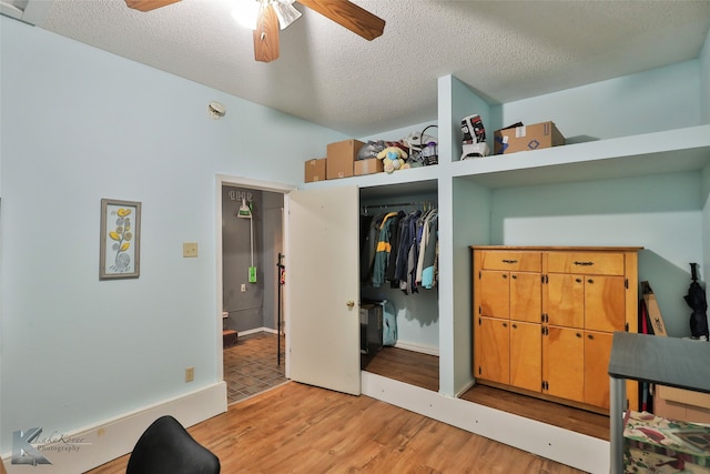 interior space featuring ceiling fan, a closet, a textured ceiling, and light hardwood / wood-style flooring