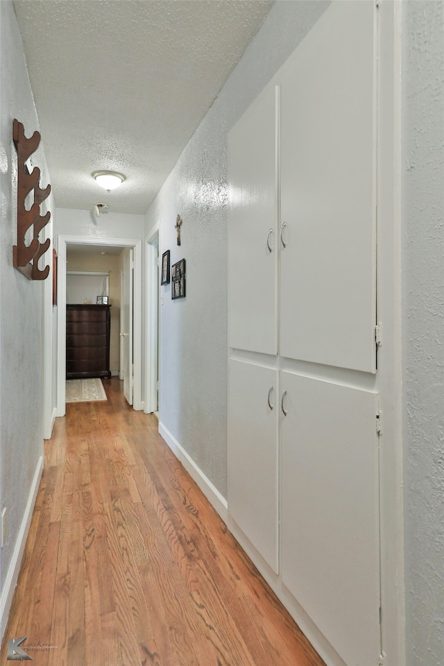 hall featuring a textured ceiling and light hardwood / wood-style flooring