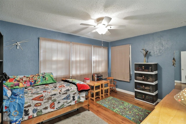 bedroom with hardwood / wood-style flooring, ceiling fan, and a textured ceiling