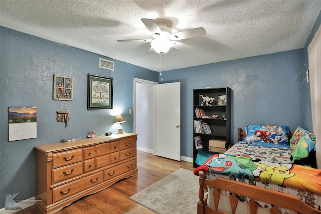 bedroom with ceiling fan, light hardwood / wood-style floors, and a textured ceiling