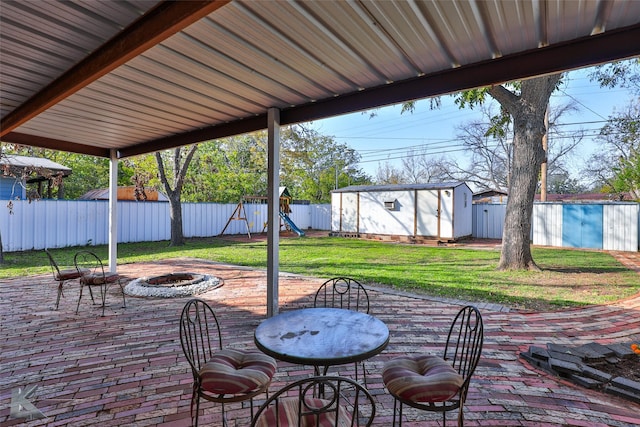 view of patio / terrace with a storage unit, a playground, and an outdoor fire pit