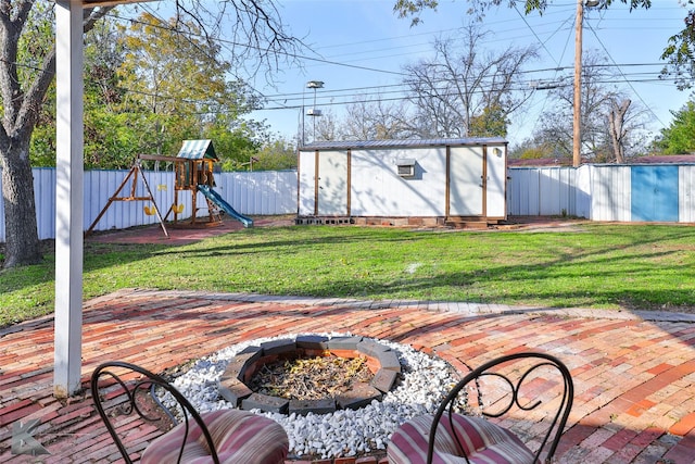 view of patio / terrace featuring a playground, a shed, and a fire pit