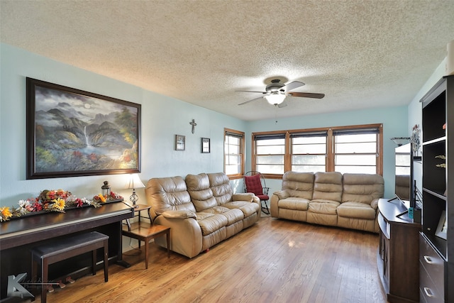 living room featuring ceiling fan, light hardwood / wood-style floors, and a textured ceiling