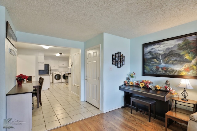 hall with washer and dryer, a textured ceiling, and light wood-type flooring