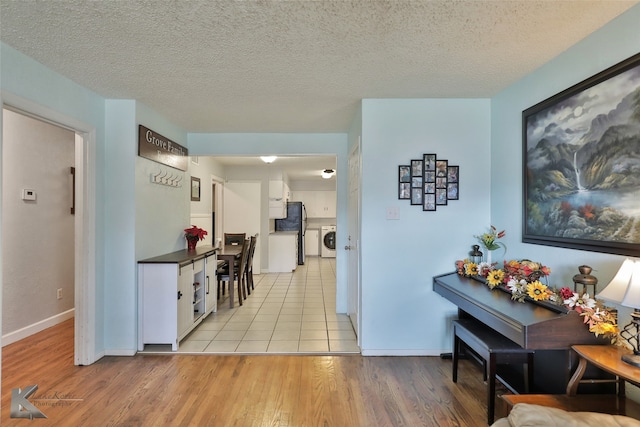 hall featuring light hardwood / wood-style floors, washing machine and dryer, and a textured ceiling