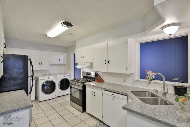 kitchen featuring dishwasher, black refrigerator, stainless steel range with gas cooktop, sink, and separate washer and dryer