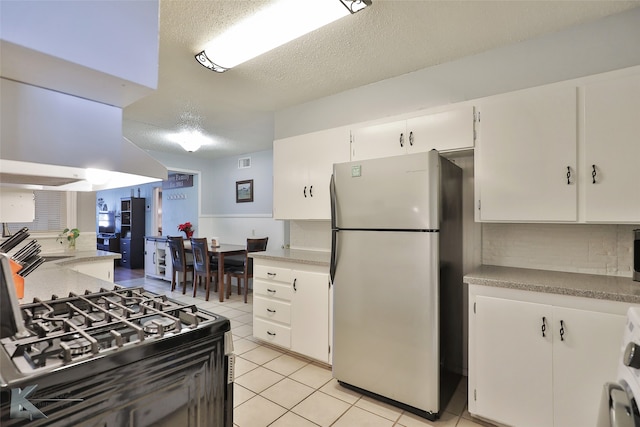 kitchen with white cabinets, light tile patterned flooring, a textured ceiling, and appliances with stainless steel finishes