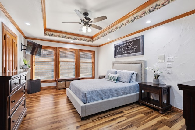 bedroom featuring hardwood / wood-style flooring, a raised ceiling, ceiling fan, and ornamental molding