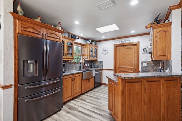 kitchen with sink, a skylight, light hardwood / wood-style floors, kitchen peninsula, and stainless steel appliances