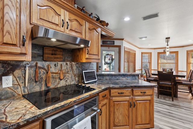 kitchen featuring decorative backsplash, stainless steel oven, hanging light fixtures, and black electric stovetop