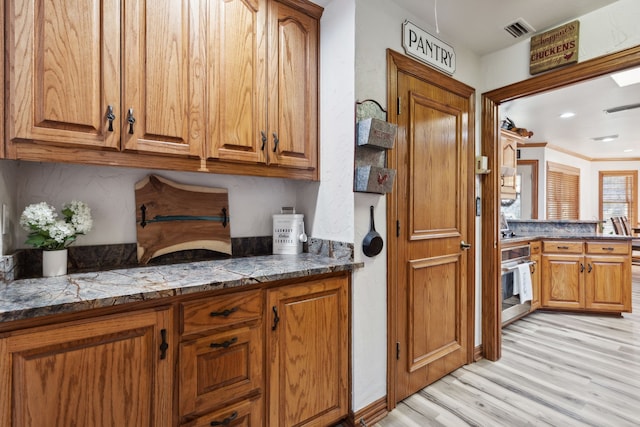 kitchen with light hardwood / wood-style flooring, oven, and ornamental molding