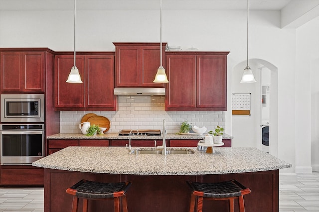 kitchen featuring sink, stainless steel appliances, hanging light fixtures, and tasteful backsplash