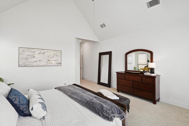 bedroom featuring light colored carpet and high vaulted ceiling