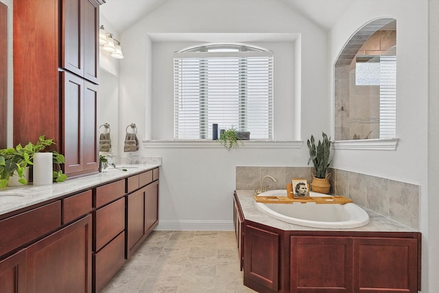 bathroom featuring vanity, lofted ceiling, and a bath