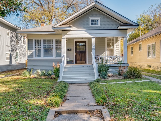 bungalow-style house featuring covered porch and a front yard