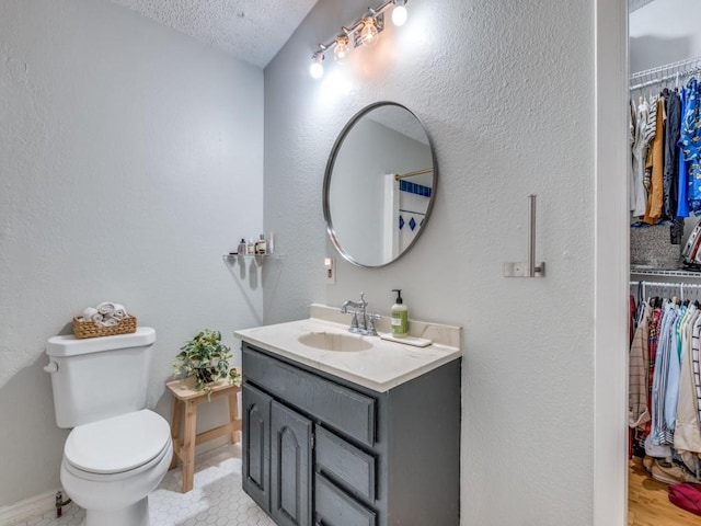 bathroom with vanity, a textured ceiling, and toilet