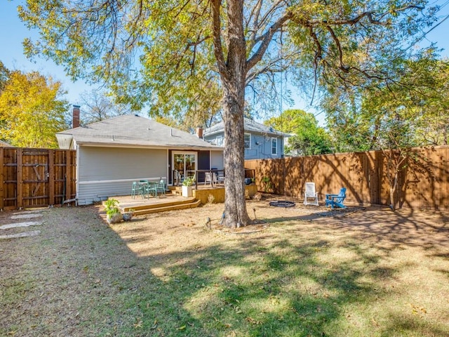 back of house with an outdoor fire pit, a yard, and a deck