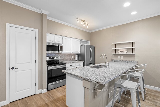 kitchen with white cabinetry, sink, kitchen peninsula, a breakfast bar, and appliances with stainless steel finishes