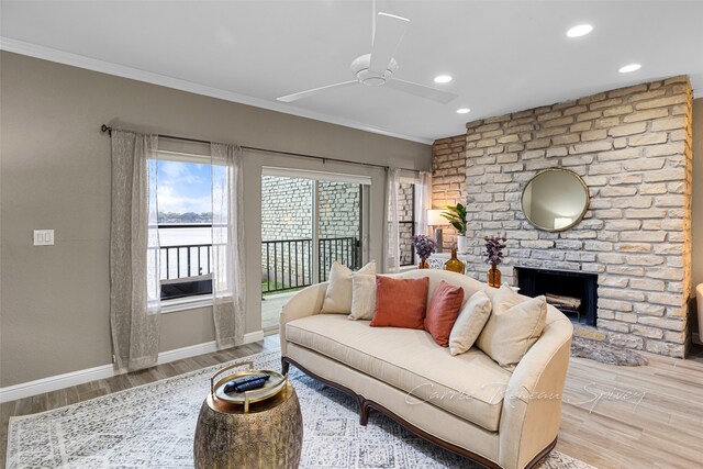 living room with a brick fireplace, crown molding, ceiling fan, and hardwood / wood-style flooring