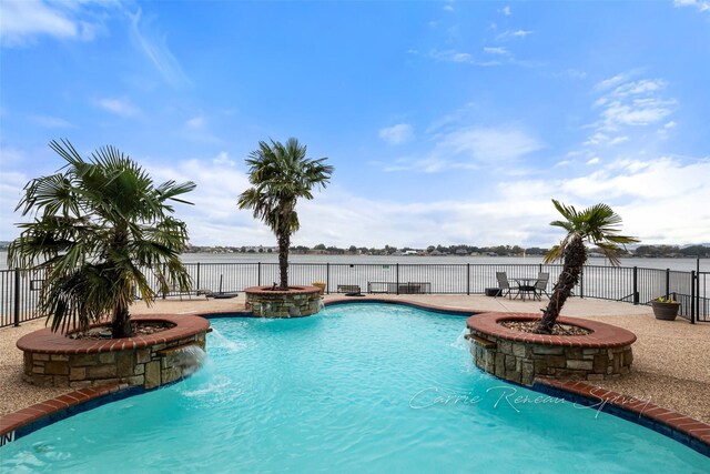 view of pool featuring pool water feature, a water view, a patio, and a hot tub