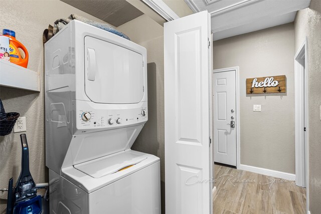 laundry area with stacked washing maching and dryer and light hardwood / wood-style flooring