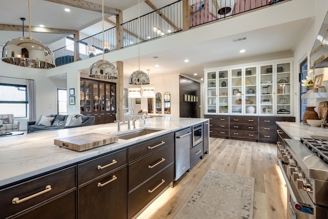 kitchen with sink, light stone counters, light hardwood / wood-style flooring, pendant lighting, and white cabinets