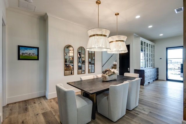 dining space with crown molding, light hardwood / wood-style floors, and a chandelier