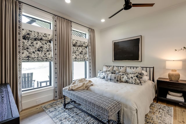 bedroom with crown molding, ceiling fan, multiple windows, and light wood-type flooring