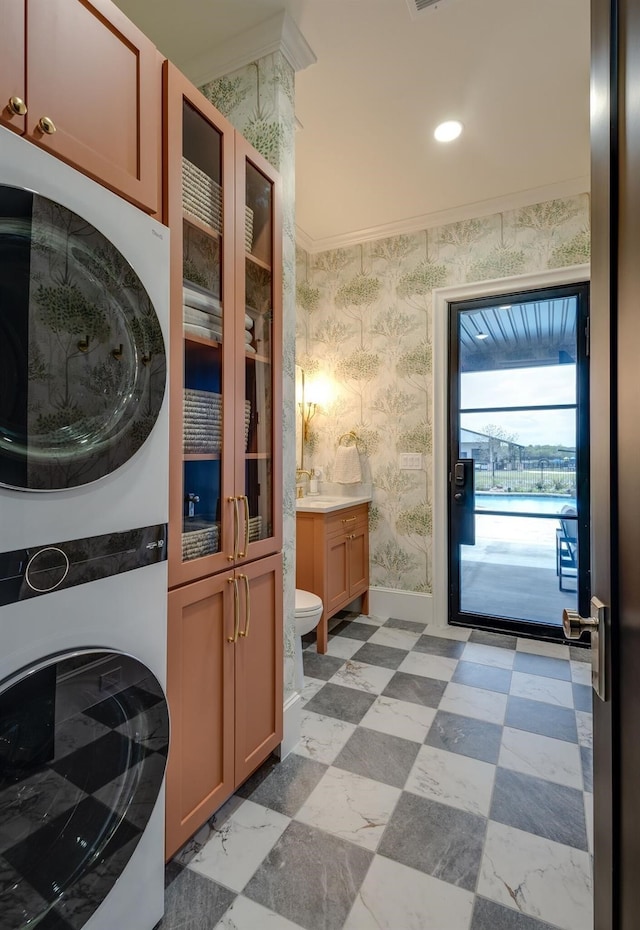 laundry area featuring ornamental molding and stacked washer / dryer