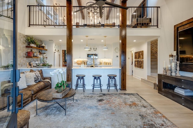 living room featuring light hardwood / wood-style floors, ceiling fan, and a high ceiling