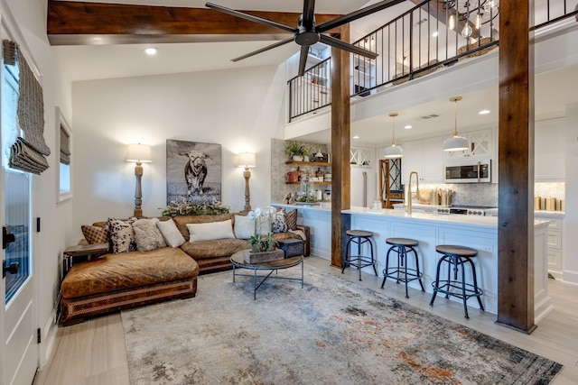 living room with beamed ceiling, high vaulted ceiling, ceiling fan, and light hardwood / wood-style flooring