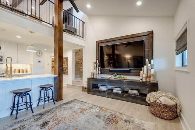 living room with sink, vaulted ceiling, and light wood-type flooring