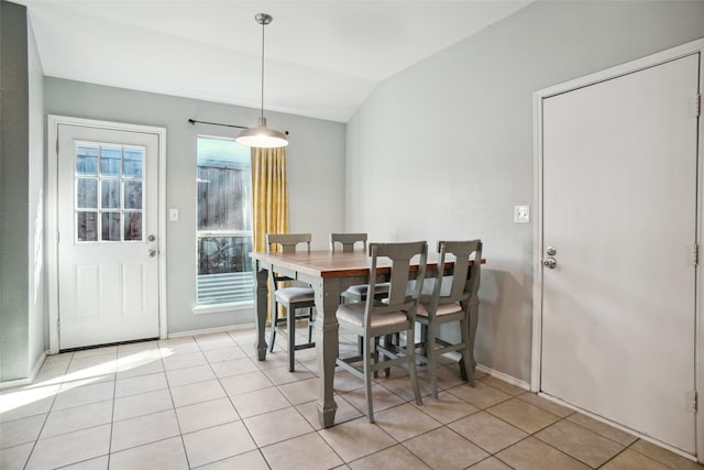 tiled dining room featuring vaulted ceiling