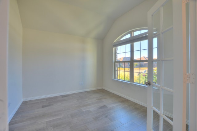 unfurnished room with light hardwood / wood-style floors and vaulted ceiling