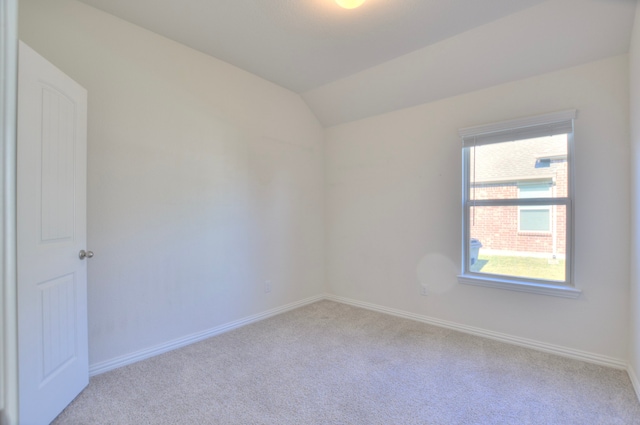 unfurnished room featuring light carpet and lofted ceiling