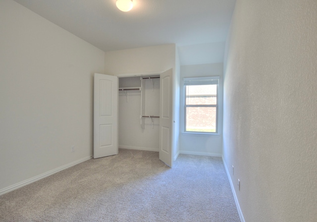 unfurnished bedroom with light carpet and a closet