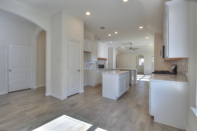 kitchen featuring white cabinets, decorative backsplash, light hardwood / wood-style floors, and ceiling fan